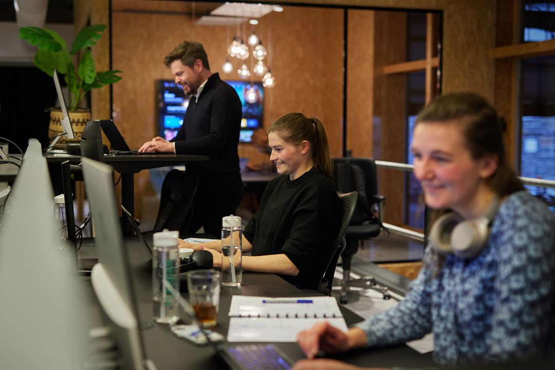Drie Cardanners zitten achter hun laptop en glimlachen