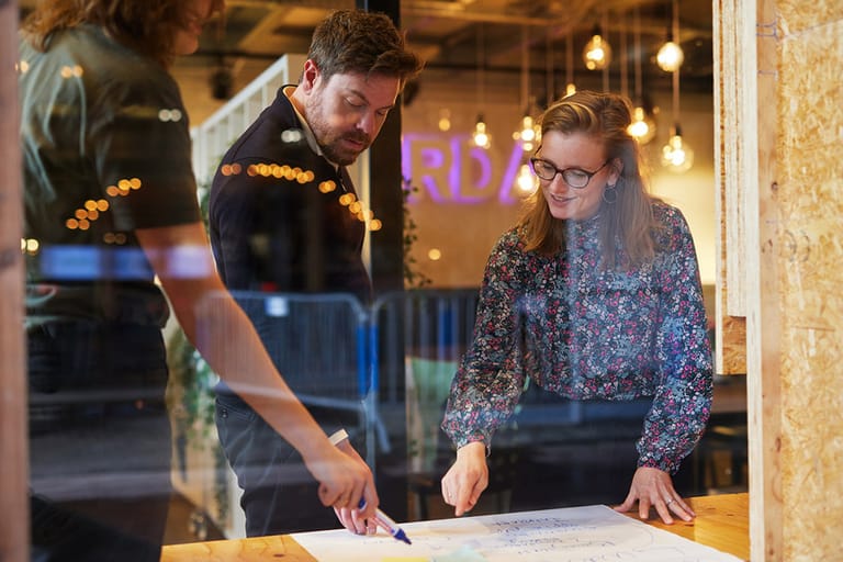 Drie Cardanners zijn aan het schrijven op een groot vel papier